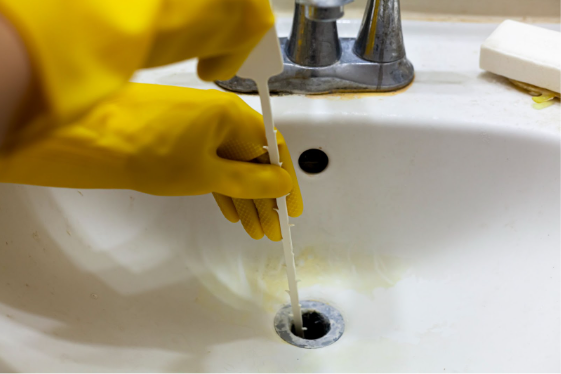 person using a sink snake to unclog a sink